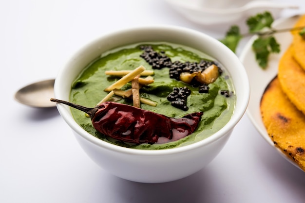 Makki di roti con sarson ka saag, popolare ricetta del piatto principale punjabi in inverno a base di pane di mais, senape e foglie di curry. servito su sfondo lunatico. messa a fuoco selettiva