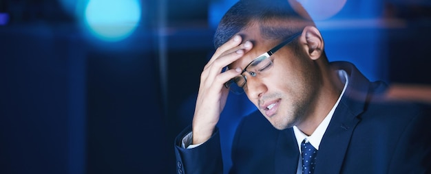 Mal di testa burnout e stress uomo d'affari che lavora fino a tardi nell'ufficio aziendale Maniaco del lavoro sente la pressione del carico di lavoro e delle scadenze frustrato e soffre di emicrania ed esausto dagli straordinari