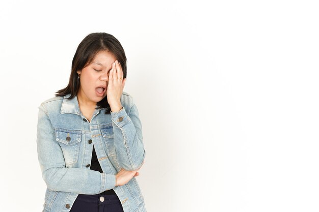 Mal di testa di bella donna asiatica che indossa giacca di jeans e camicia nera isolata su sfondo bianco