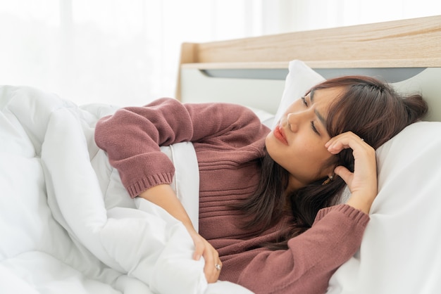 Mal di testa donna asiatica e dormire sul letto