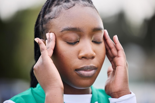 Mal di testa sportivo e volto di donna nera all'aperto con ansia da stress o esaurimento su sfondo sfocato Allenamento dell'emicrania e atleta donna africana con massaggio al tempio per vertigini nebbia cerebrale o dolore