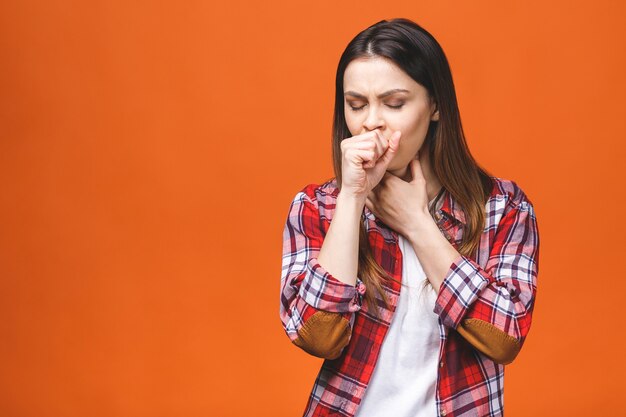 Malata giovane donna bruna in camicia a quadri, con mal di gola, tenendo la mano sul collo