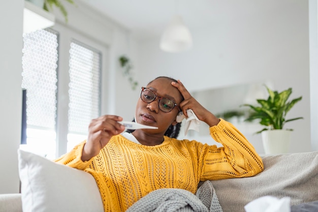 Malattia concetto di problema di virus stagionale Donna malata con l'influenza sdraiata a letto a guardare la temperatura sul termometro Donna malata seduta a letto con febbre alta Influenza fredda coronavirus covid-19