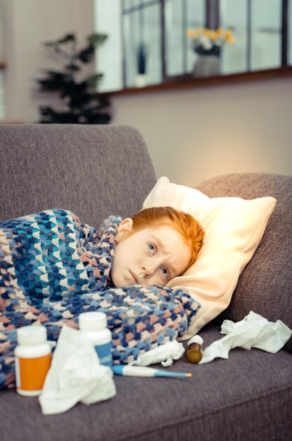 Malattia sgradevole. Ragazza triste triste che riposa sul divano mentre soffre di influenza