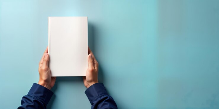 Photo male hand holding blank hardcover business book mockup on blue banner empty book cover displays