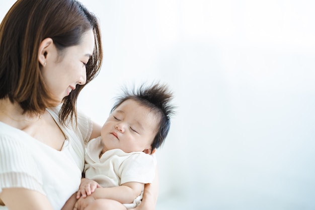 Mamma asiatica che tiene in braccio un bambino nella stanza luminosa