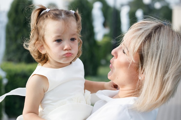 Mamma bionda che tiene una piccola figlia nel parco in estate con tempo soleggiato