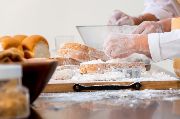 Mamma che insegna al bambino a cucinare il cibo. Preparare un ingrediente con polvere e pane.