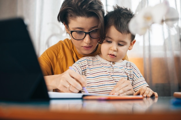 Mamma che insegna con amore a suo figlio che scrive il tempo della famiglia