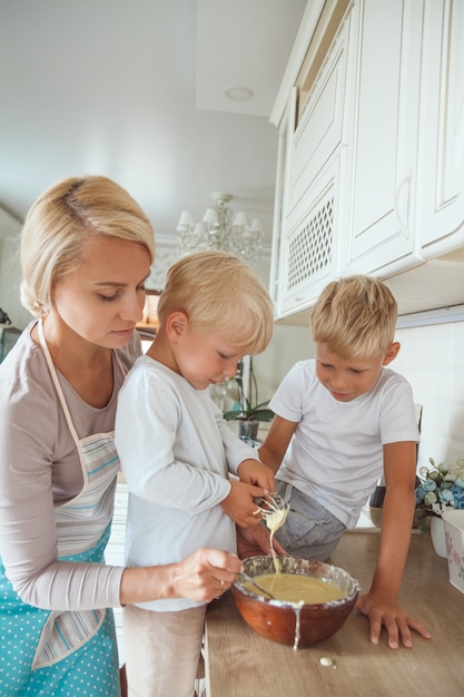 Mamma con due figli che cucinano la torta di festa in cucina. Vita casuale