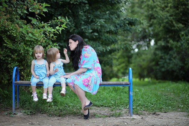 Mamma con due figlie gemelle per una passeggiata nel parco