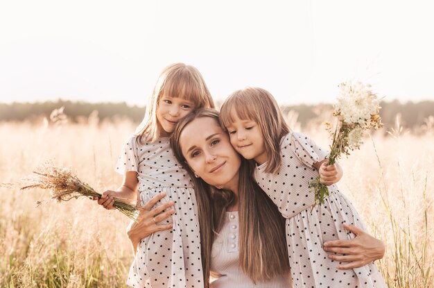 Mamma con due gemelle che giocano nella natura in estate