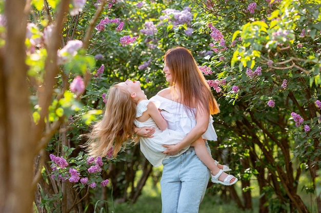 Mamma con un bambino in braccio durante una passeggiata nel giardino lilla primaverile nel parco concetto di famiglia felice