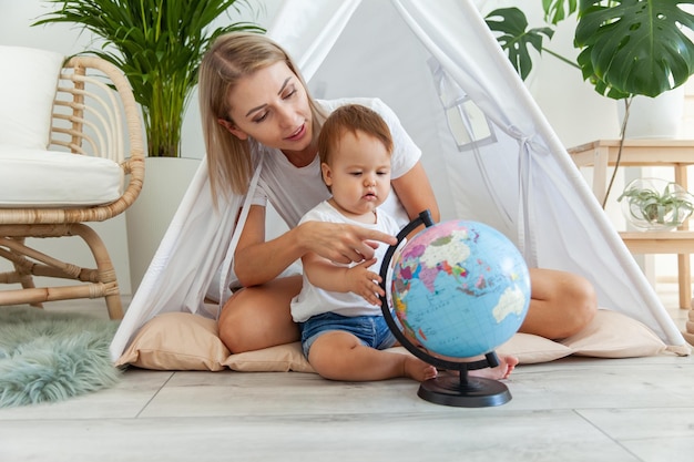Mamma con una bambina seduta in un wigwam a casa a studiare il globo Passare del tempo insieme concetto di Matyrdom