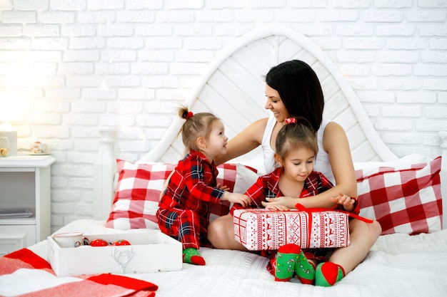 Mamma e bambini ridono allegramente mentre la ragazza più grande apre un regalo di Natale