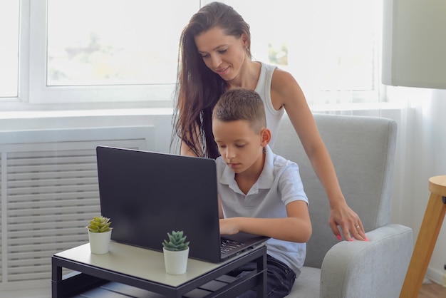 mamma e bambino felici che fanno i compiti insieme alla famiglia del computer