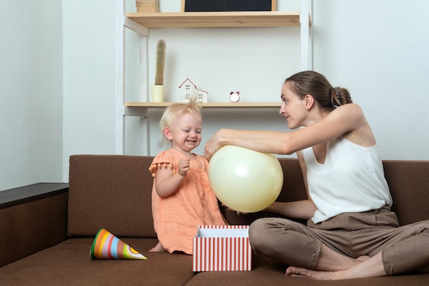 Mamma e bambino giocano con il palloncino a casa sul divano Divertente preparazione per le vacanze