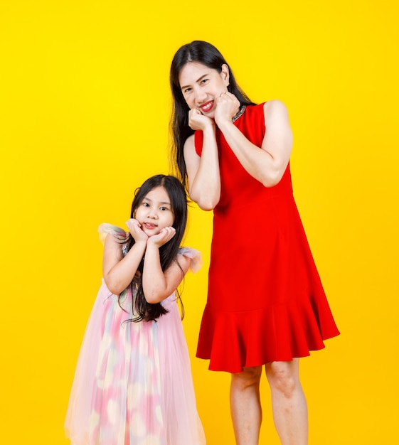 Mamma e figlia asiatiche che scattano foto ritratto insieme su sfondo giallo con divertenti e adorabili.