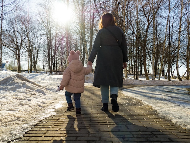 Mamma e figlia camminano mano nella mano in una calda giornata primaverile