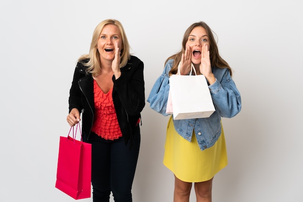 Mamma e figlia che comprano alcuni vestiti isolati su bianco gridando e annunciando qualcosa