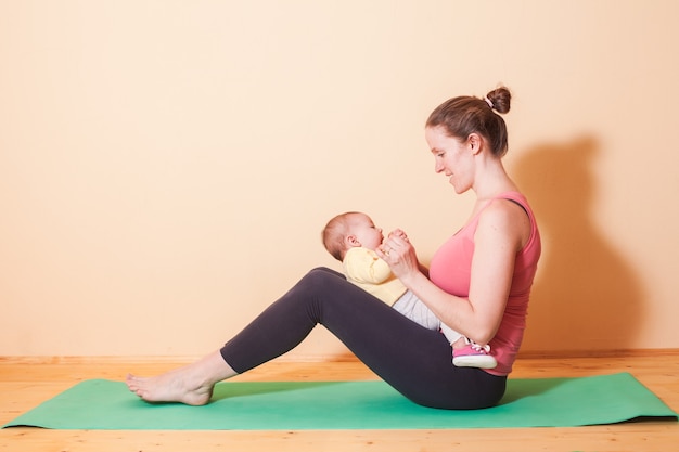 Mamma e figlia che fanno esercizi di yoga sul tappeto verde