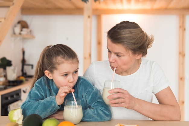 Mamma e figlia che mangiano frutta e bevono frullato