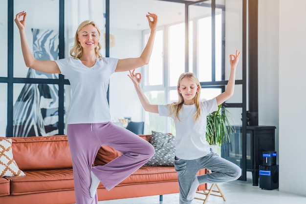 Mamma e figlia che praticano yoga a casa uno stile di vita familiare sano