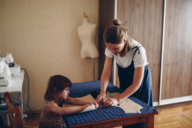 Mamma e figlia cucono insieme i vestiti. Abito fantasia.