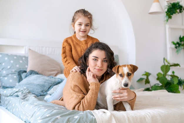 Mamma e figlia felici giocano con il loro adorabile Jack Russell Terrier cablato