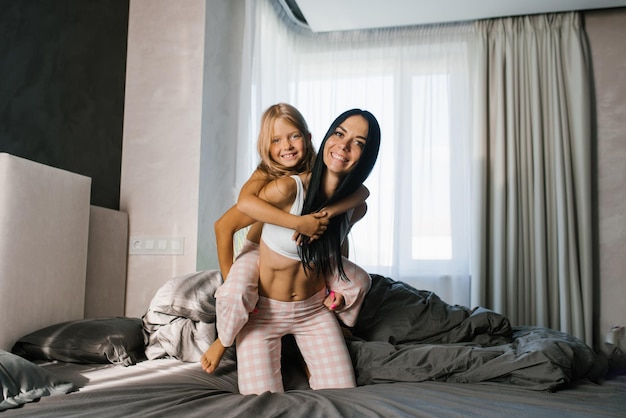 Mamma e figlia felici ridono e si divertono a letto la mattina