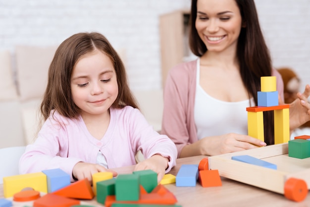 Mamma e figlia giocano insieme con cubetti di legno.