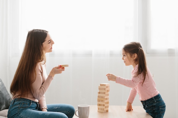 Mamma e figlia giocano un gioco da tavolo in salotto.