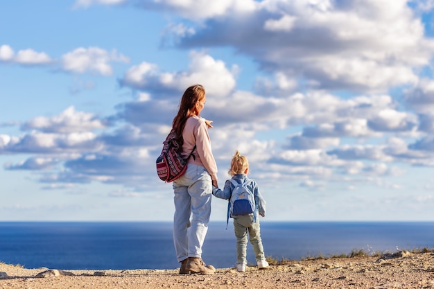 Mamma e figlia hanno scalato una montagna e guardano il mare con le spalle alla telecamera