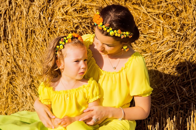 Mamma e figlia in abiti gialli su un campo di fieno