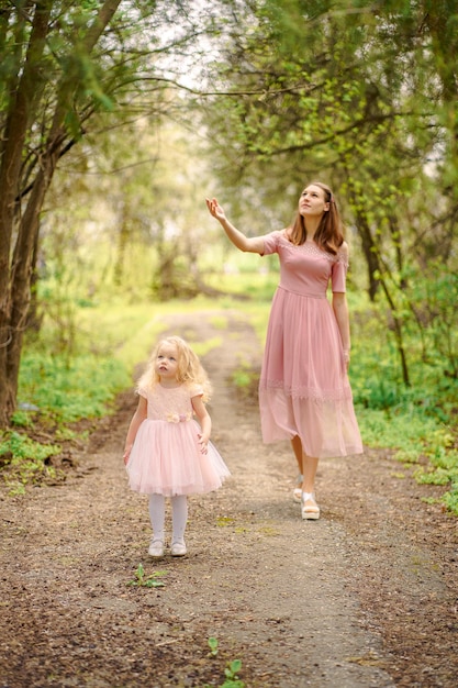 mamma e figlia in abiti rosa nella foresta di primavera