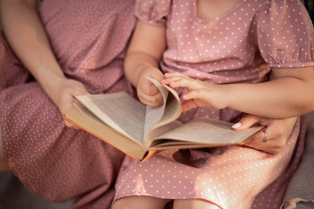 Mamma e figlia in abiti rosa stanno leggendo un libro Libro nelle mani di una ragazza