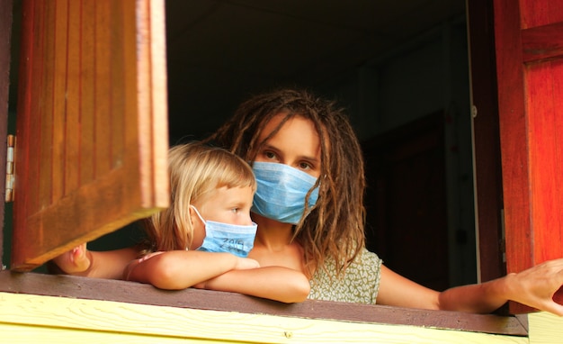 Mamma e figlia in maschera di quarantena a casa in isolamento