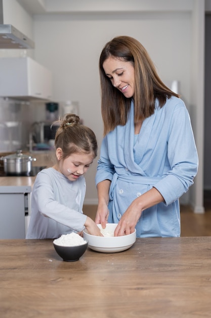 Mamma e figlia insieme in cucina impastano la pasta in una ciotola Concetto di cucina insieme a casa Copia spazio