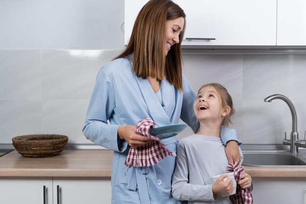 Mamma e figlia insieme in cucina puliscono i piatti con gli asciugamani Concetto di aiuto per genitori Copia spazio