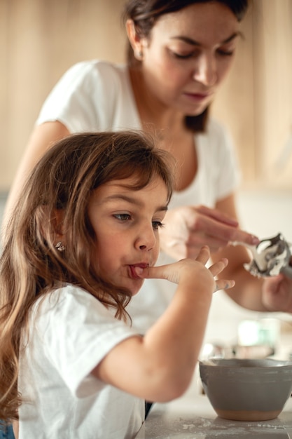 Mamma e figlia preparano la glassa per il pan di zenzero nella loro cucina di casa. Batti con un frullatore. La ragazza