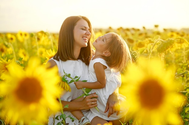 Mamma e figlia ridono allegramente in un campo di girasoli Tenerezza cura e amore dei genitori per i bambini Armonia e unità con la natura Giornata mondiale dell'infanzia