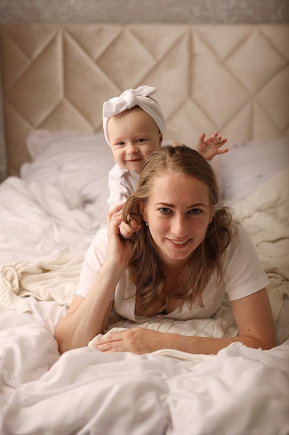 mamma e figlia si coccolano su un lenzuolo bianco maternità