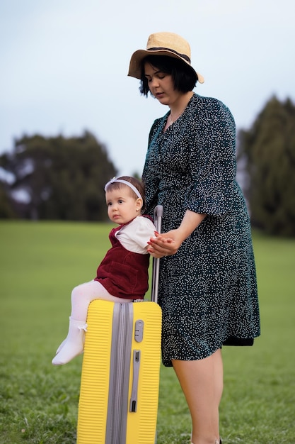 Mamma e figlia si stanno preparando per il viaggio Una bambina siede su una valigia gialla