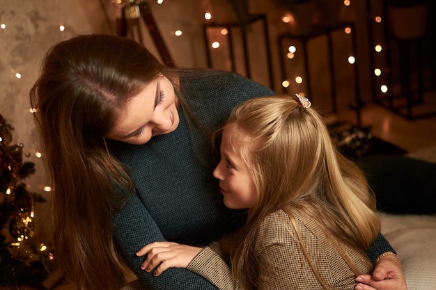 Mamma e figlia sono sedute vicino all'albero di Natale