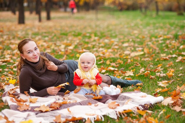 Mamma e figlia stanno giocando nel parco d'autunno.