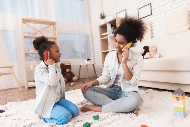 Mamma e figlia stanno giocando sul pavimento con cubi di legno.