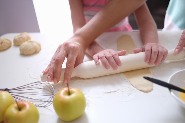 Mamma e figlia stendono la pasta con il mattarello