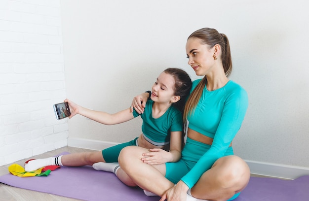 Mamma e figlia vengono fotografate al telefono durante le lezioni di fitness a casa