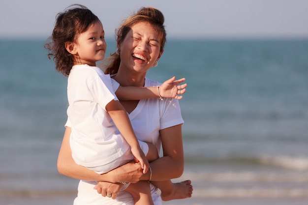 Mamma e figlio asiatici giocano sulla spiaggia tropicale tropical