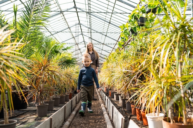 Mamma e figlio camminano in una serra con le piante